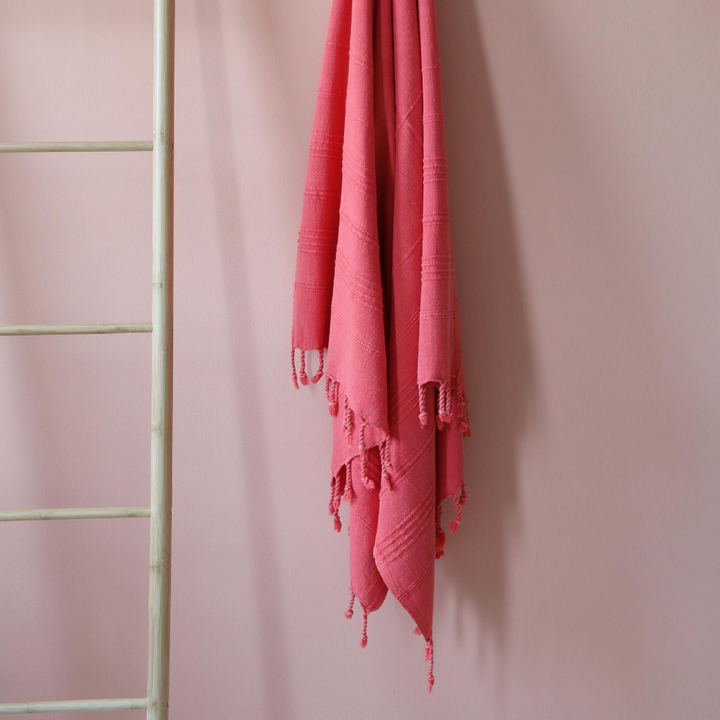 Stone-washed, vermilion red Turkish peshtemal hanging on a wall